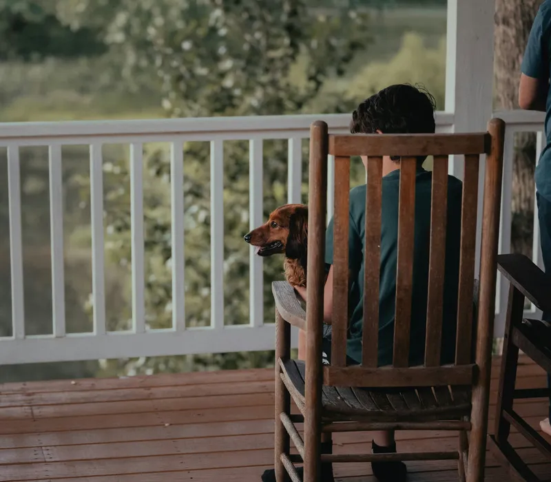 A homeowner relaxing on the porch with their dog in a clean backyard